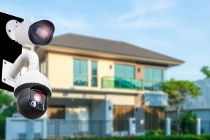 Surveillance camera stationed outside of a home during the daytime.