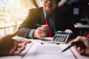 Person calculating taxes sitting at a desk with papers holding a calculator