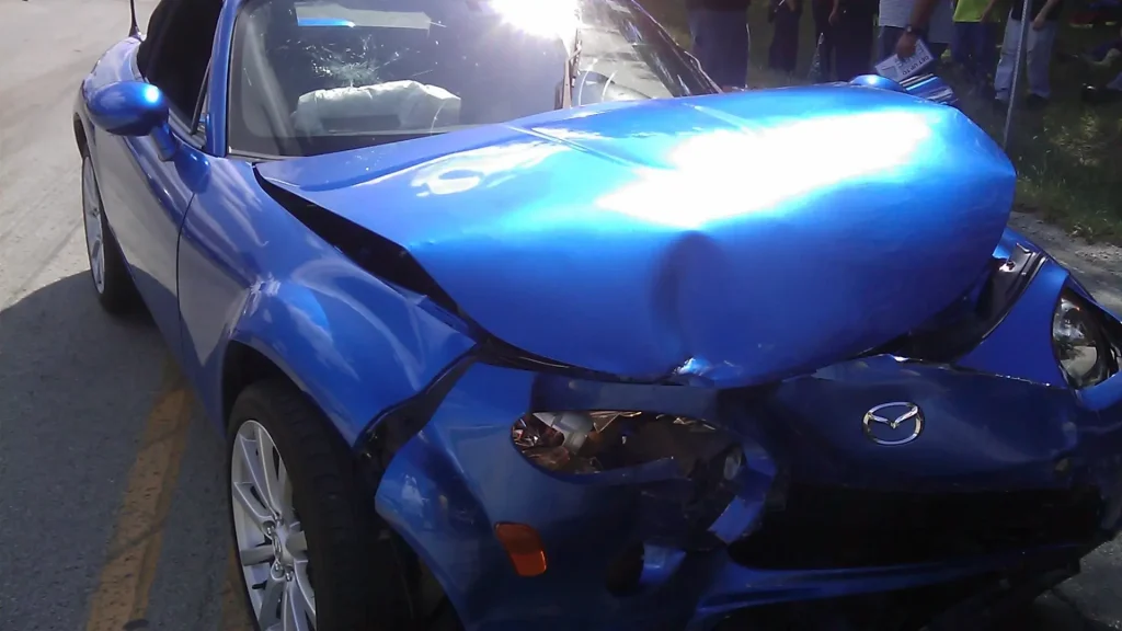 Close-up of a blue car with significant front-end damage after a collision