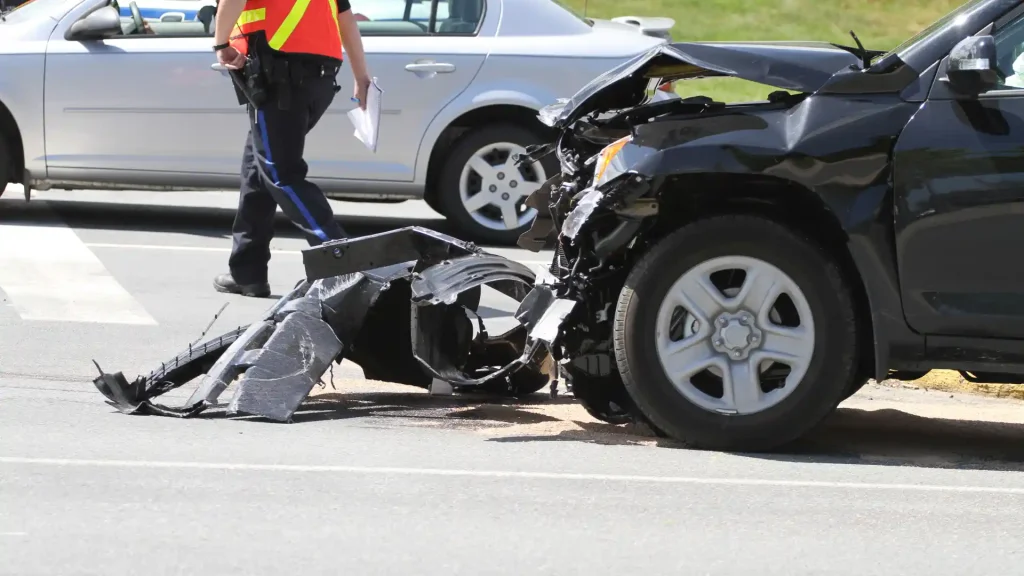 Police officer inspecting the scene of a car accident with damaged vehicles