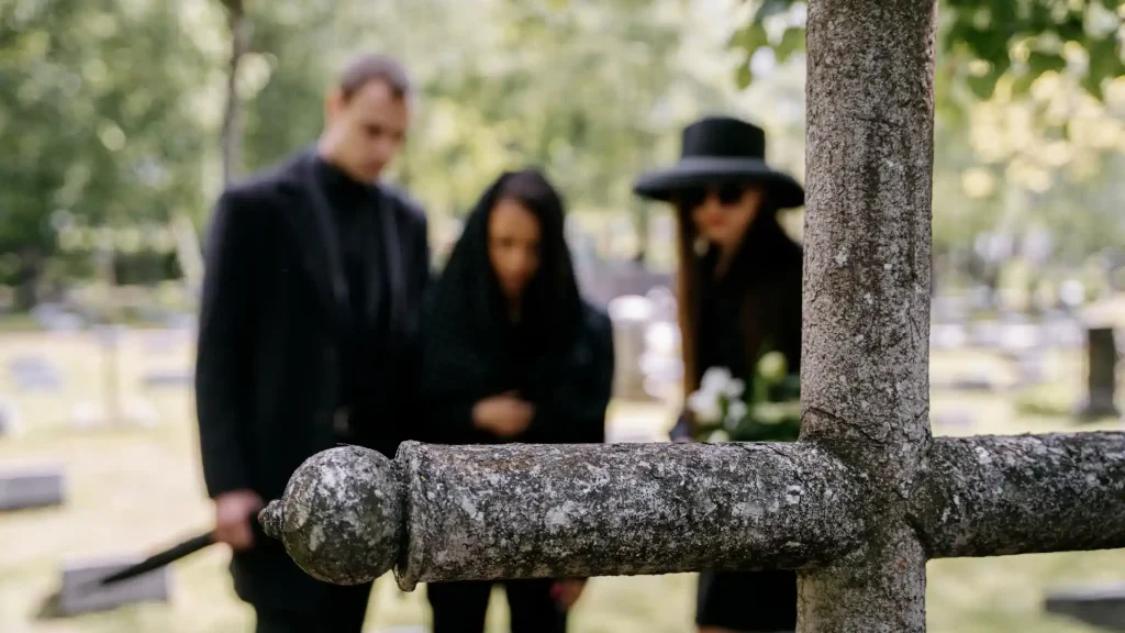 Family in mourning at a gravesite, with focus on gravestone